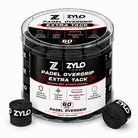 A clear plastic tub of ZYLO Padel Padel Overgrip Extra Tack grip tape, shown with two loose black grip rolls in front on a white background.